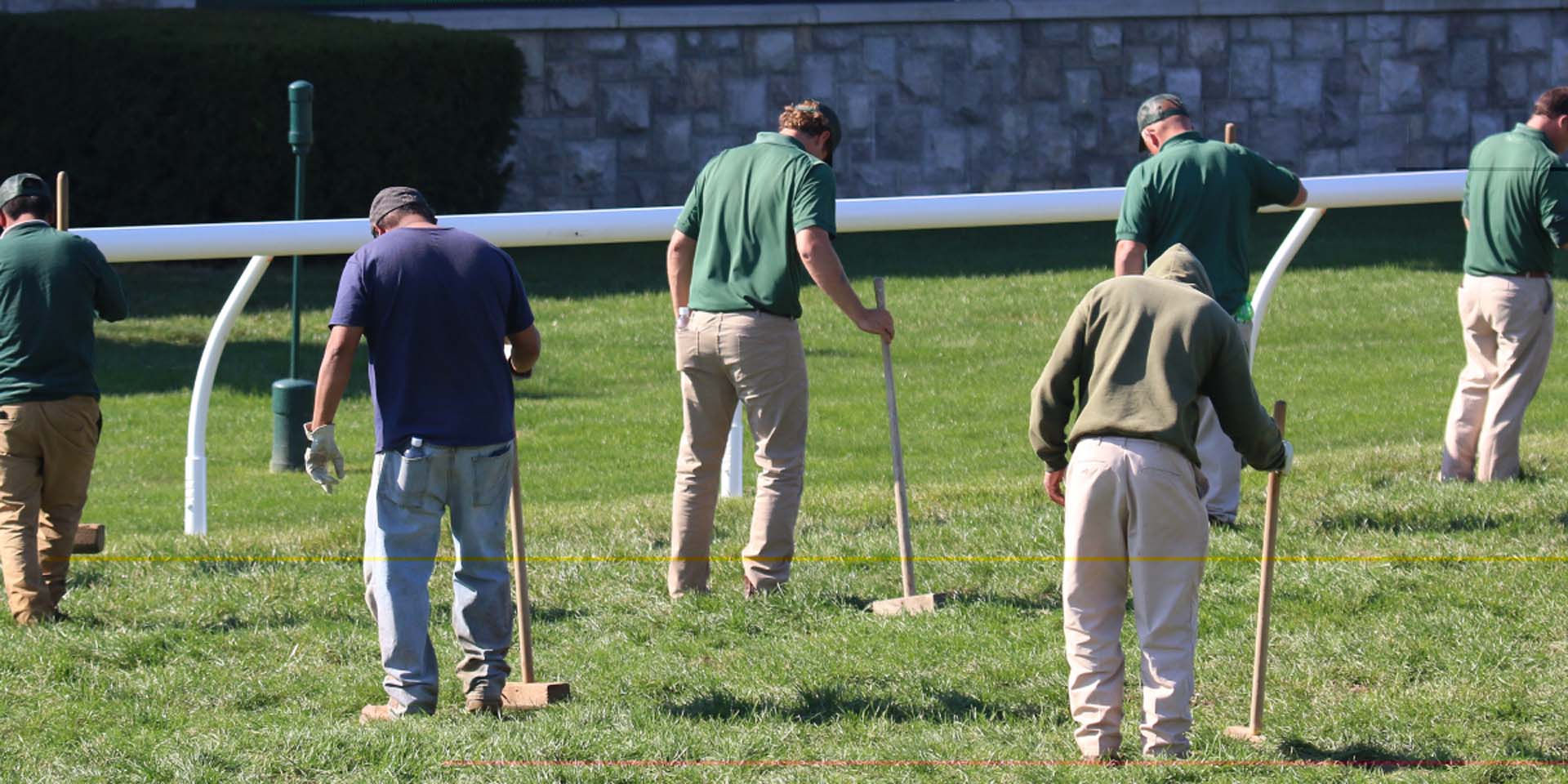 An action shot of Horseracejockey team members tamping down turf divots.
